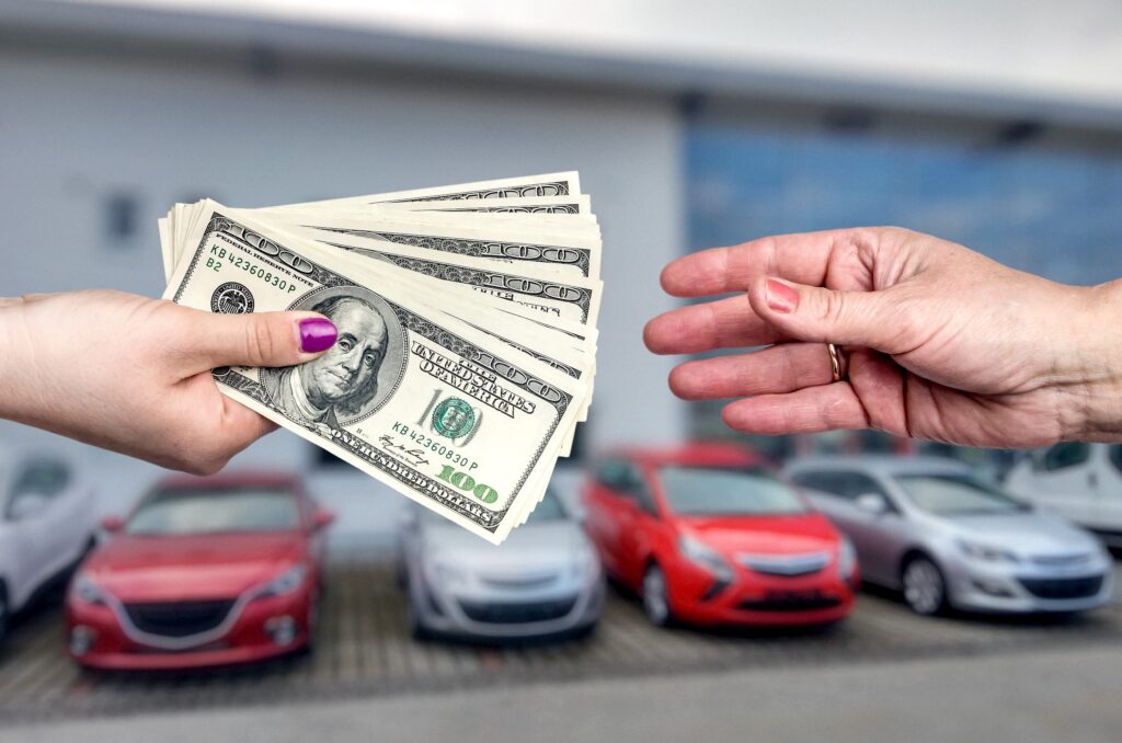 A hand gives dollars to a receiving hand in front of a line of parked cars.
URL: ev-tax-credits