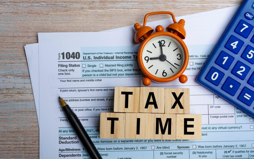 A pen, calculator, small alarm clock, and blocks spelling Tax Time are placed on a US individual income tax form.